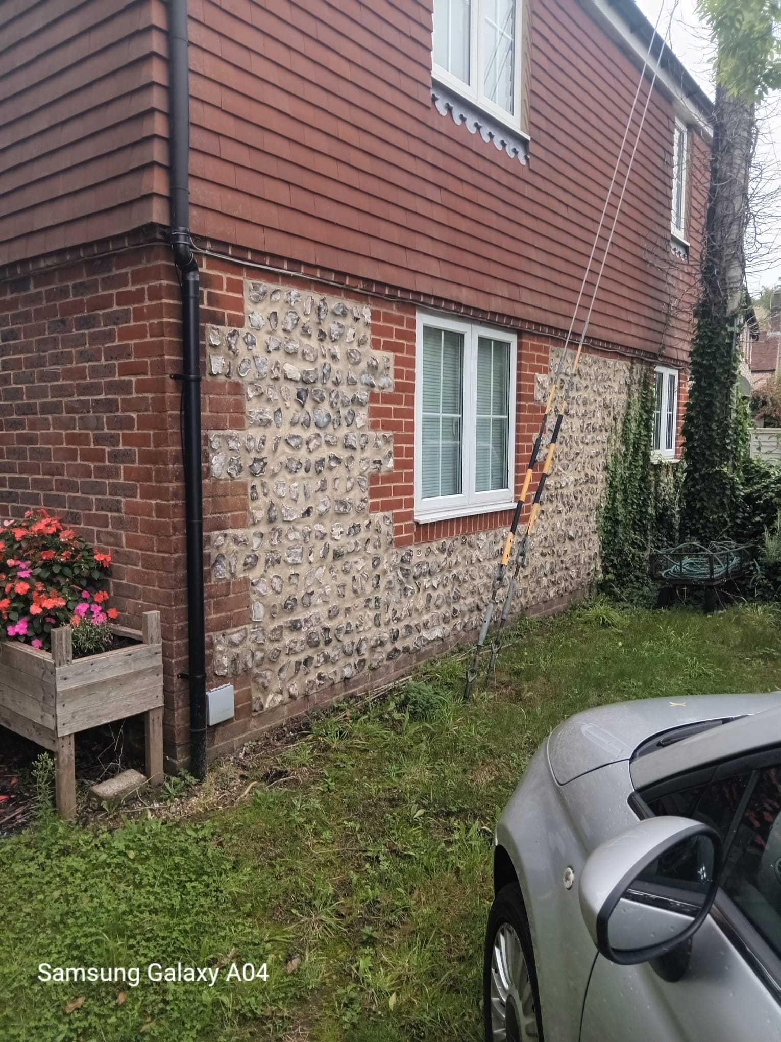 Traditional flint and red-brick wall repair to the side of a house