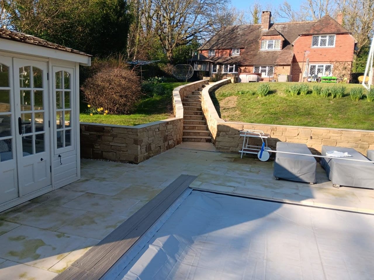 Curved natural stone garden staircase and Indian sandstone patio beside a summer house, Sussex