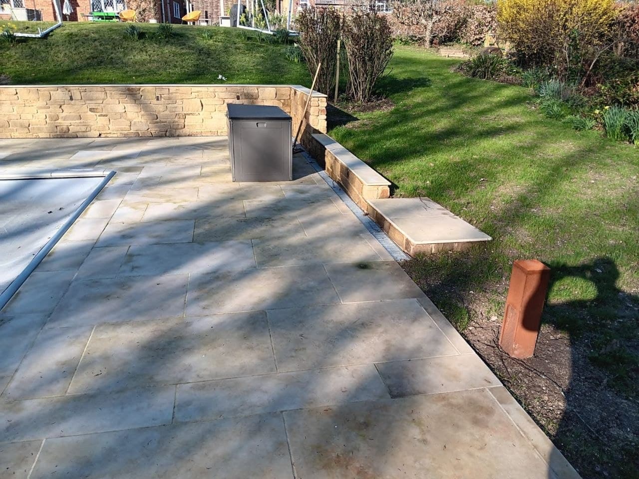 Sandstone patio and steps beside a natural stone retaining wall and lawn