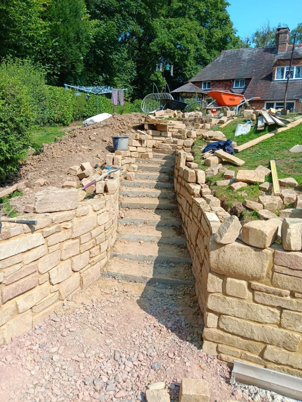 Natural stone retaining walls and steps taking shape across a sloping garden