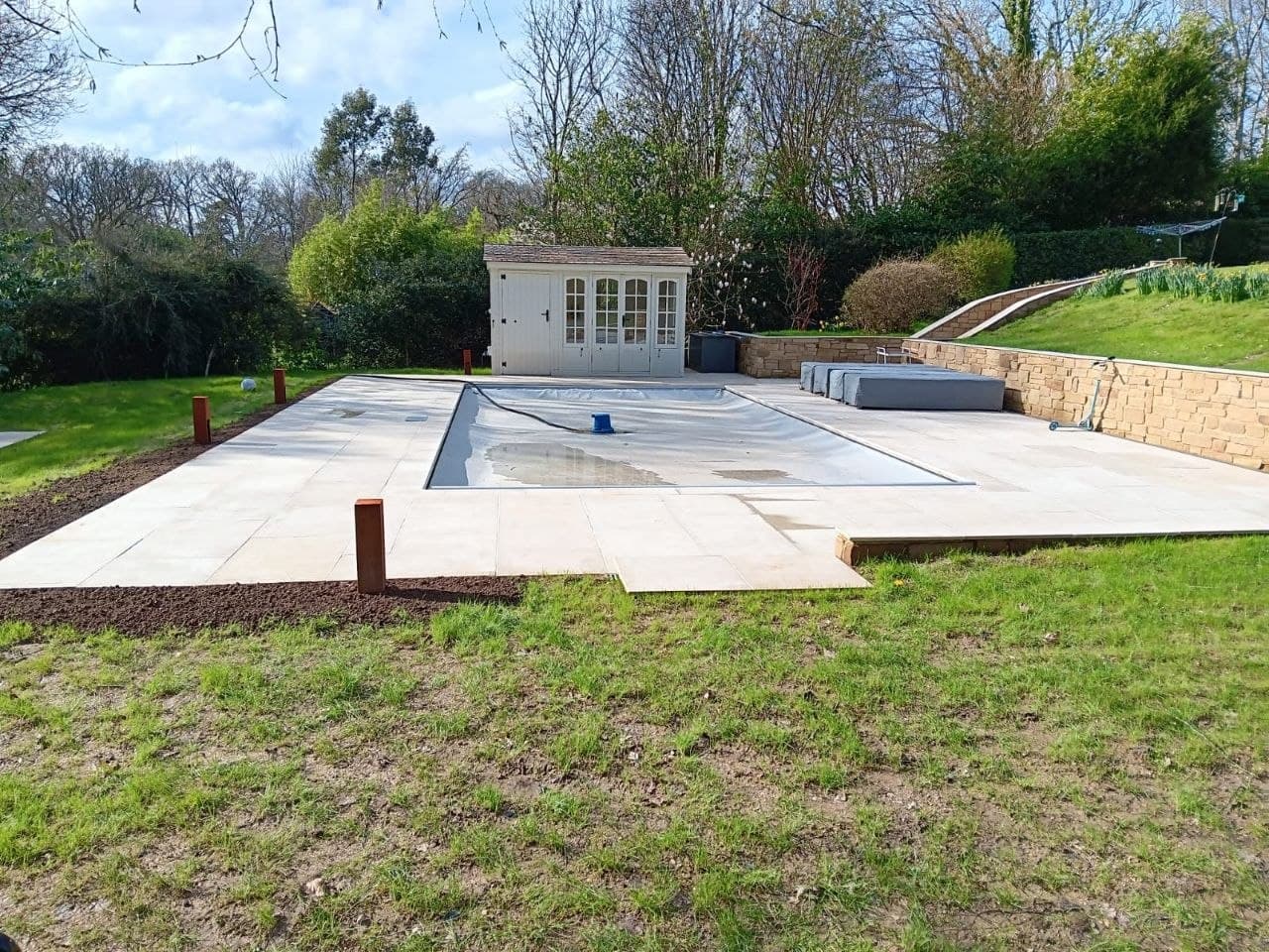 Finished pool terrace with a summer house and natural stone retaining wall
