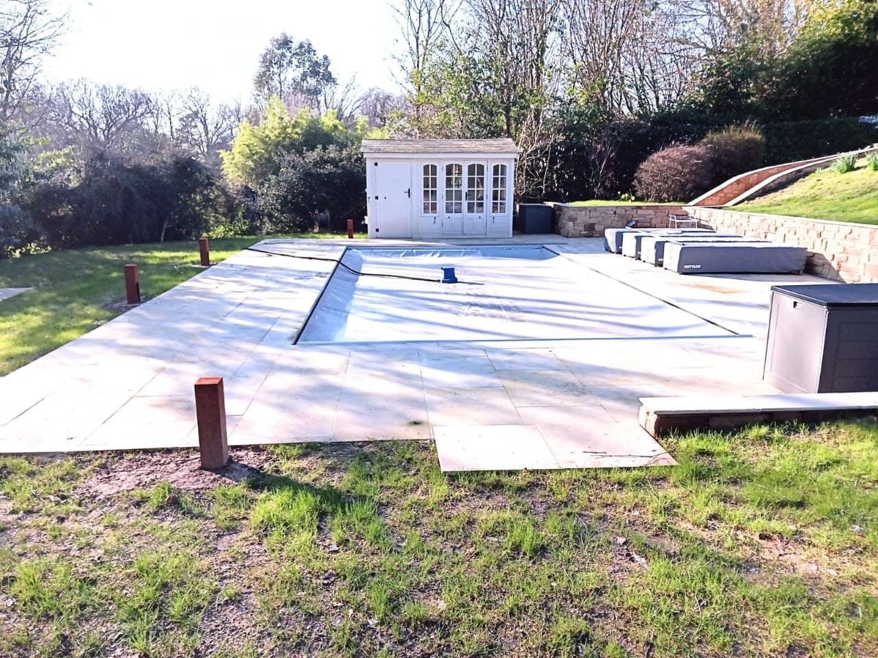 Completed pool surround with sandstone paving, summer house and stone terracing