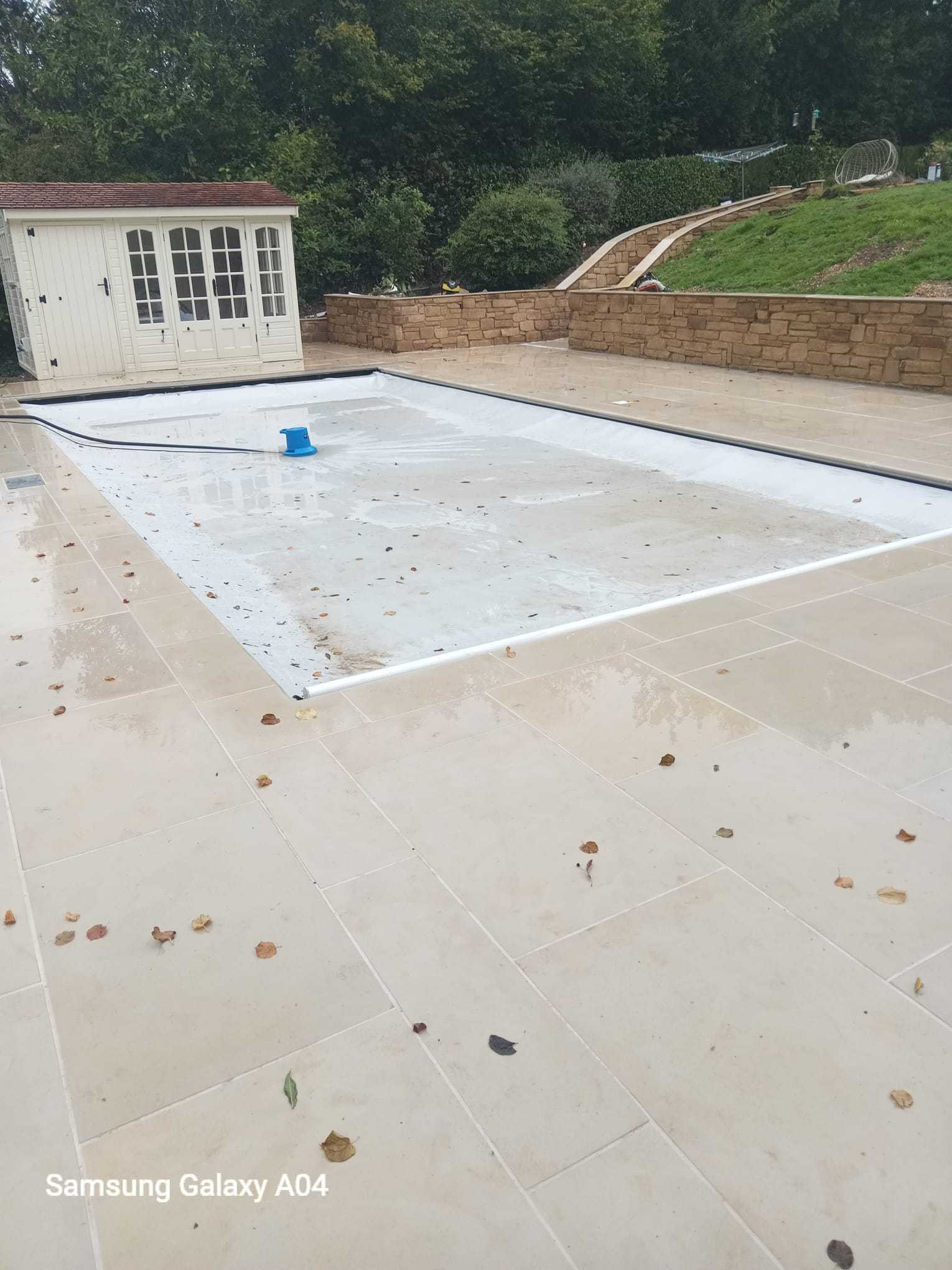Large Indian sandstone patio with a summer house and stone retaining wall